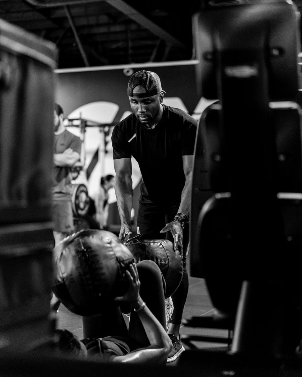 The coach is helping a client working out in the gym.